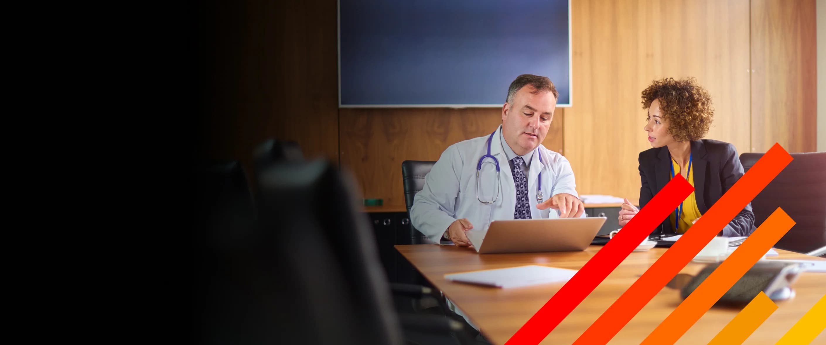 Doctor and legal professional consulting in a conference room with a laptop on the table